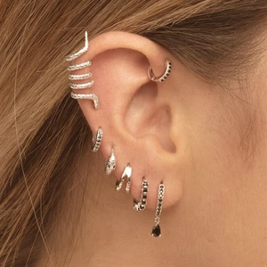 Close-up of silver layered snake ear cuff and black gemstone earrings set on ear
