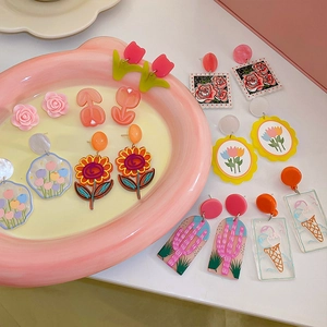 Gros plan de boucles d'oreilles fleuries en acrylique coloré avec roses et tulipes