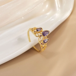 Detail of a gold crown ring with purple teardrop stones on white porcelain