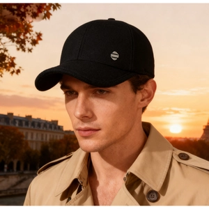 Detail of wool baseball cap with silver metal emblem against sunset city backdrop