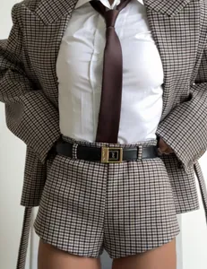 Detail of plaid blazer and shorts set with white shirt, brown tie, and black belt