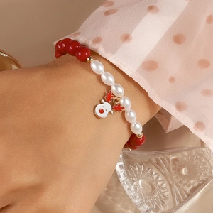 Close-up of Christmas beaded bracelet with red beads and cute reindeer charm on wrist