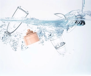 Base del frullatore rosa impermeabile e tazze trasparenti lavate con spruzzi d'acqua