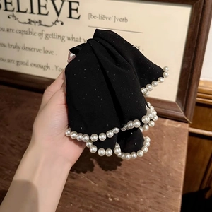 Detail of elegant black velvet hair claw clip with faux pearls and sparkling glitter