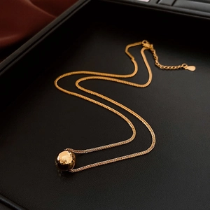 Detail shot of 18K gold plated ball pendant with hammered texture on black leather tray