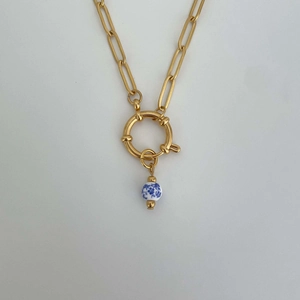Detailed shot of golden chain necklace with blue and white porcelain bead pendant