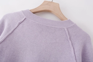 Close-up of lavender knit sweater featuring ribbed crewneck and exposed raglan seams