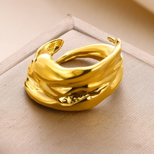 Close-up of irregular gold molten textured open ring on champagne brushed gift box