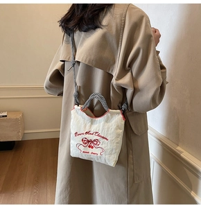 Detail of white nylon bag with red cherry embroidery and checkered woven strap