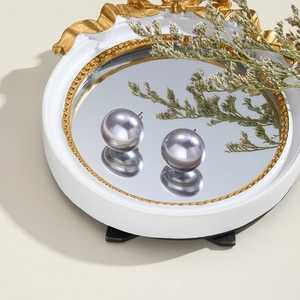 Detailed view of elegant grey faux pearl stud earrings on a vintage mirror surface