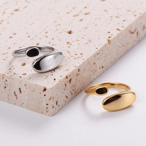 Close-up of minimalist adjustable stainless steel rings in gold and silver on stone