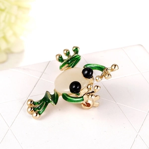 Detail einer goldenen Froschbrosche mit grüner Emaille und milchigem Katzenaugenstein