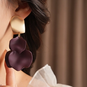 Close-up of stylish gold and deep purple floral earrings worn by a model
