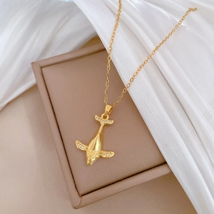Elegant gold titanium whale necklace with sparkling crystals on jewelry box display