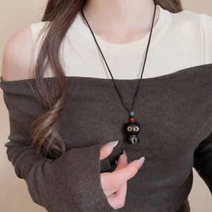 Cute black cat pendant necklace on woven cord worn by model with minimalist design