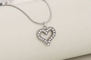 Close-up of heart pendant necklace with shimmering crystals on a silver snake chain