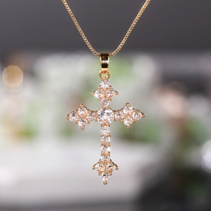 Macro detail of rose gold cross pendant with sparkling zircon inlay and box chain