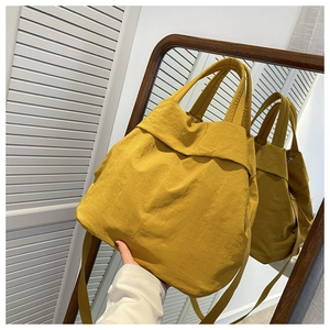 Macro view of a yellow nylon tote bag showing textured fabric and mirrored reflection