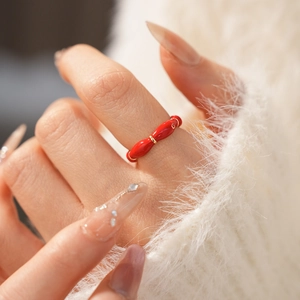 Detailed close-up of red enamel gold plated oval ring on soft white knit sweater