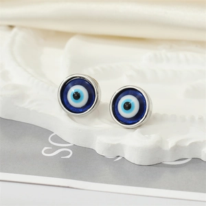 Close-up of sparkling resin Evil Eye stud earrings on a white embossed tray