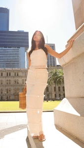 Detail of white sleeveless chiffon two-piece set featuring pleated crop top and tiered skirt