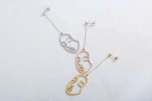 Vue détaillée des boucles d'oreilles visage abstrait en or, argent et or rose
