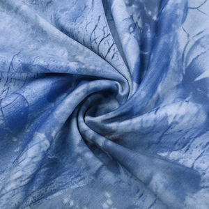 Détail du tissu imprimé bleu avec motifs artistiques et texture douce à volants