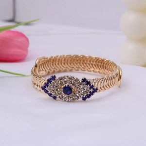 Macro detail of gold braided bracelet featuring evil eye charms with blue and white crystals