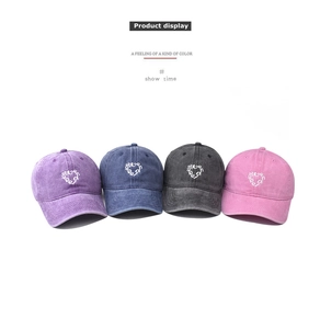 Detail view of washed cotton baseball caps with embroidered heart and letter patterns