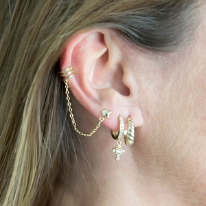 Detailed view of gold multi-layered earring set with cross charm and star chain