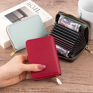 Close-up of accordion leather card holders in red, blue and brown on a wooden table