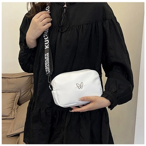 Detail of white nylon crossbody bag with silver butterfly and lettered wide strap