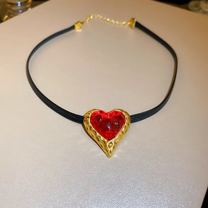 Macro detail of a vintage heart pendant with red crystal and textured gold frame