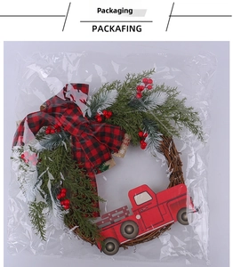Detail eines Weihnachtskranzes mit rotem Truck und Tannennadeln in Klarsichtfolie