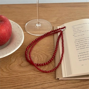 Close-up of double-layer red agate bead necklace on minimalist wooden tabletop