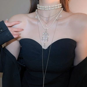 Close-up of layered pearl choker necklace with rhinestone cross pendants on a model