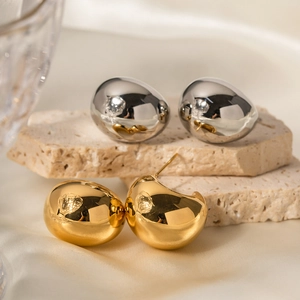 Minimalist 18k gold and silver geometric drop-shaped earrings on stone background