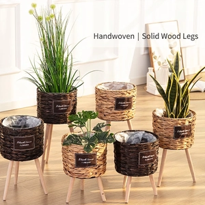 Handwoven grass flowerpot with wooden legs and plastic lining in a bright home setting