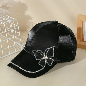 Close-up of black velvet baseball cap featuring rhinestone butterfly and brim details