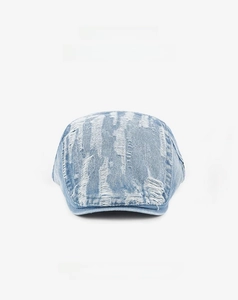 Close-up of light blue denim flat cap featuring vintage distressed ripped hole details