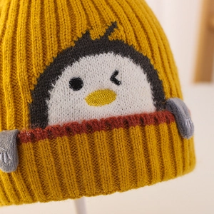 Primer plano del gorro de punto amarillo para bebé con bordado de pingüino tierno