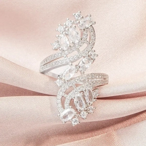 Luxury silver-tone wave ring featuring sparkling zircon stones on a pink silk background
