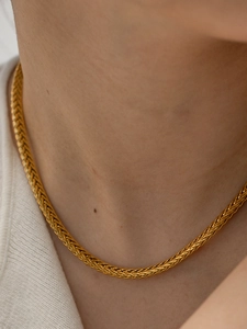 Dettaglio di una collana a catena intrecciata placcata oro 18K sul collo di un modello