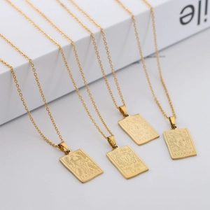 Detailed view of four golden rectangular zodiac pendants on chains over white steps