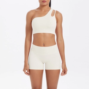 Detail of cream one-shoulder sports bra and high-waisted shorts yoga set on model
