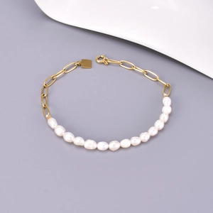 Detail of 18K gold plated paperclip chain and freshwater pearl link bracelet with charm
