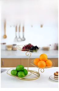Three-tier golden iron fruit basket with leaf-shaped wire trays on kitchen counter