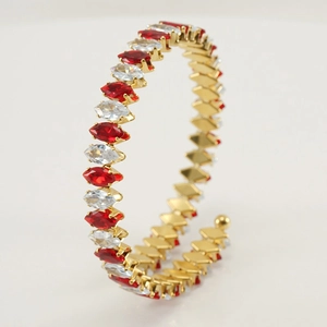 Detail view of gold stainless steel bangle with red and clear marquise-cut stones
