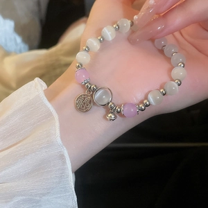 Close-up of cat eye stone bead bracelet with Fu character charm and tiny bell