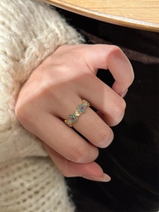 Detail of 18k gold plated flower ring with blue enamel and red zircon on a woman hand